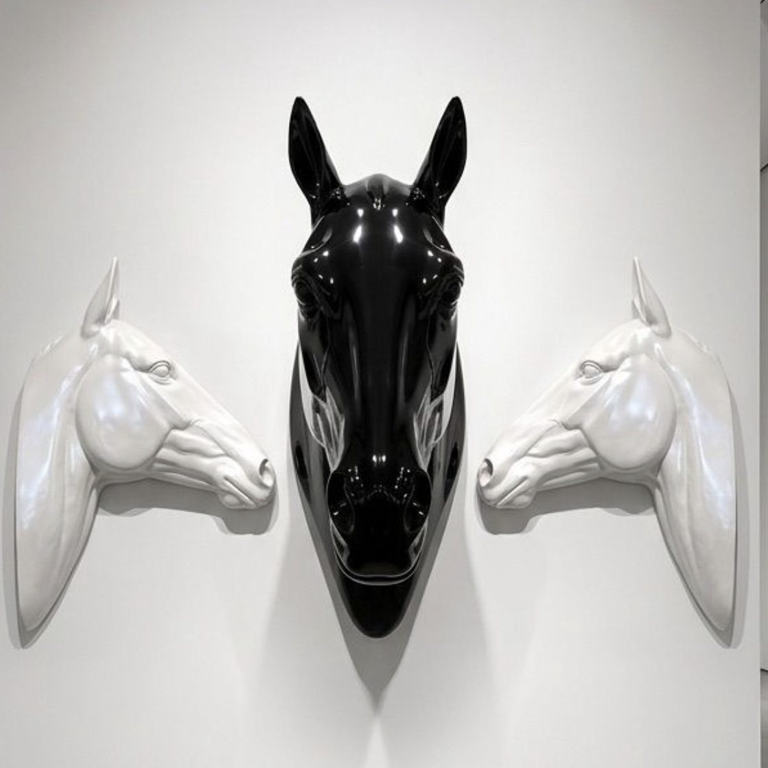 Three sculptural horse heads, black and white, wall-mounted, made in the studio